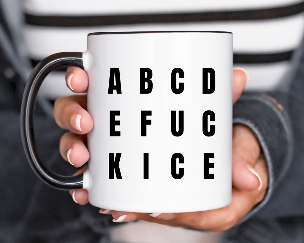 White mug with black text reading ABCDE FUCK ICE held by a person, with a blurred background