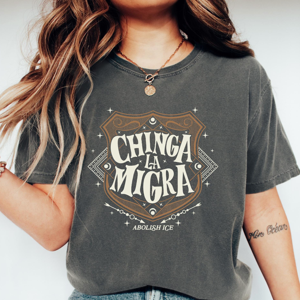 Person wearing a gray t-shirt with 'Chinga La Migra abolish ice' text design.