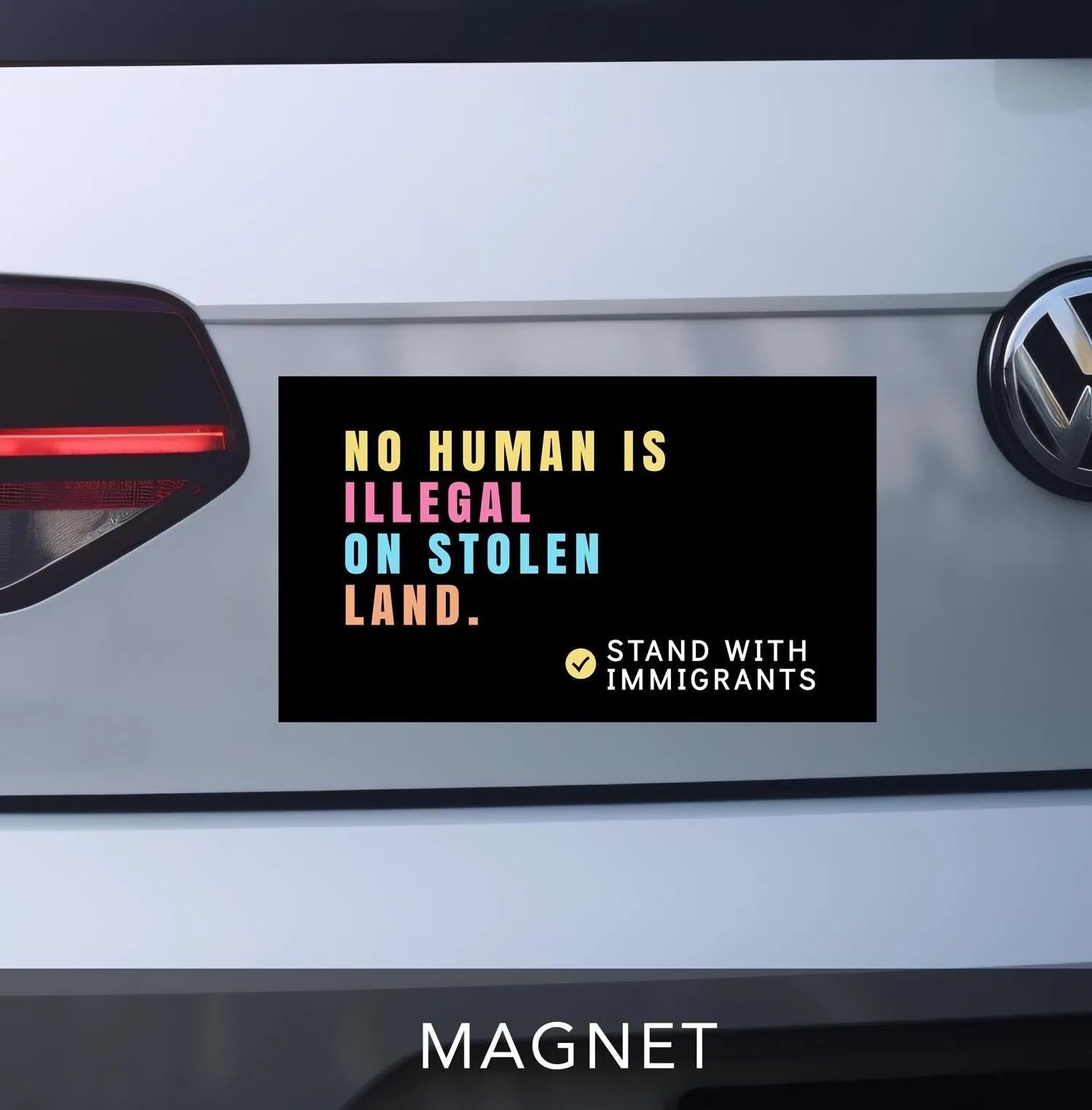 No human is illegal on stolen land magnet for car bumper. black with pastel block lettering. reads &quot;stand with immigrants&quot; in bottom right corner.