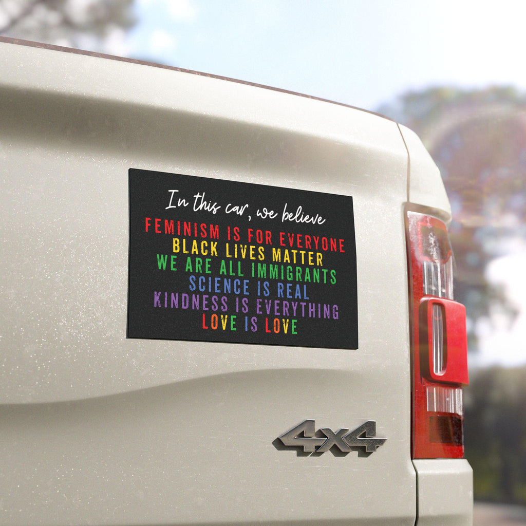 Rainbow car bumper magnet with distressed block lettering that reads: “In this car, we believe: science is real, black lives matter, love is love, we are all immigrants, feminism is for everyone, and kindness is everything.”