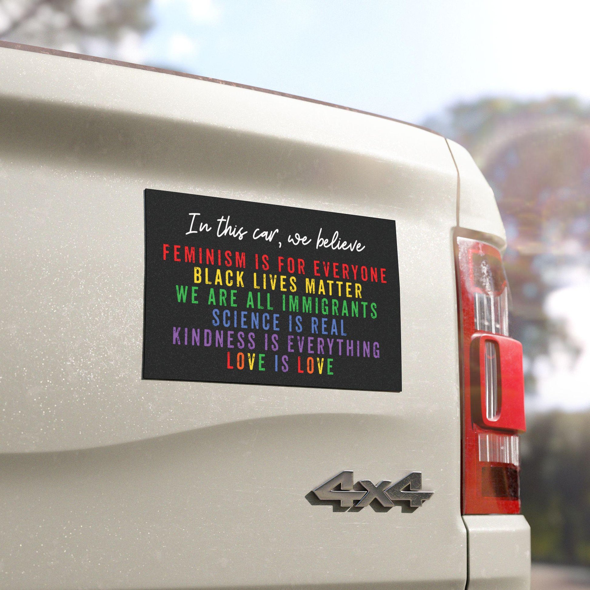Rainbow car bumper magnet with distressed block lettering that reads: “In this car, we believe: science is real, black lives matter, love is love, we are all immigrants, feminism is for everyone, and kindness is everything.”