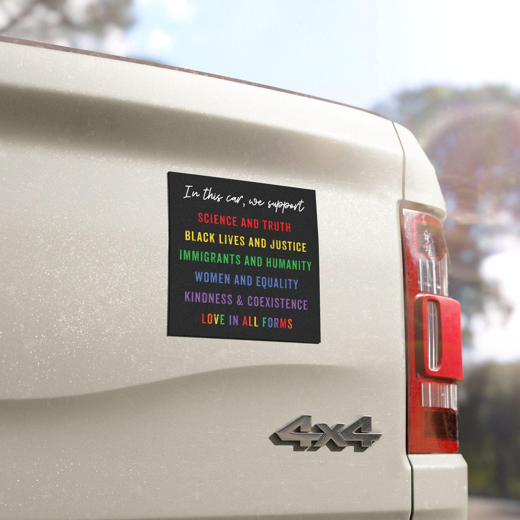Magnet with the text “In this car, we support: science and truth, black lives and justice, immigrants and humanity, women and equality, kindness, unity and coexistence, love in all forms” on a rainbow background, displayed on a car bumper.