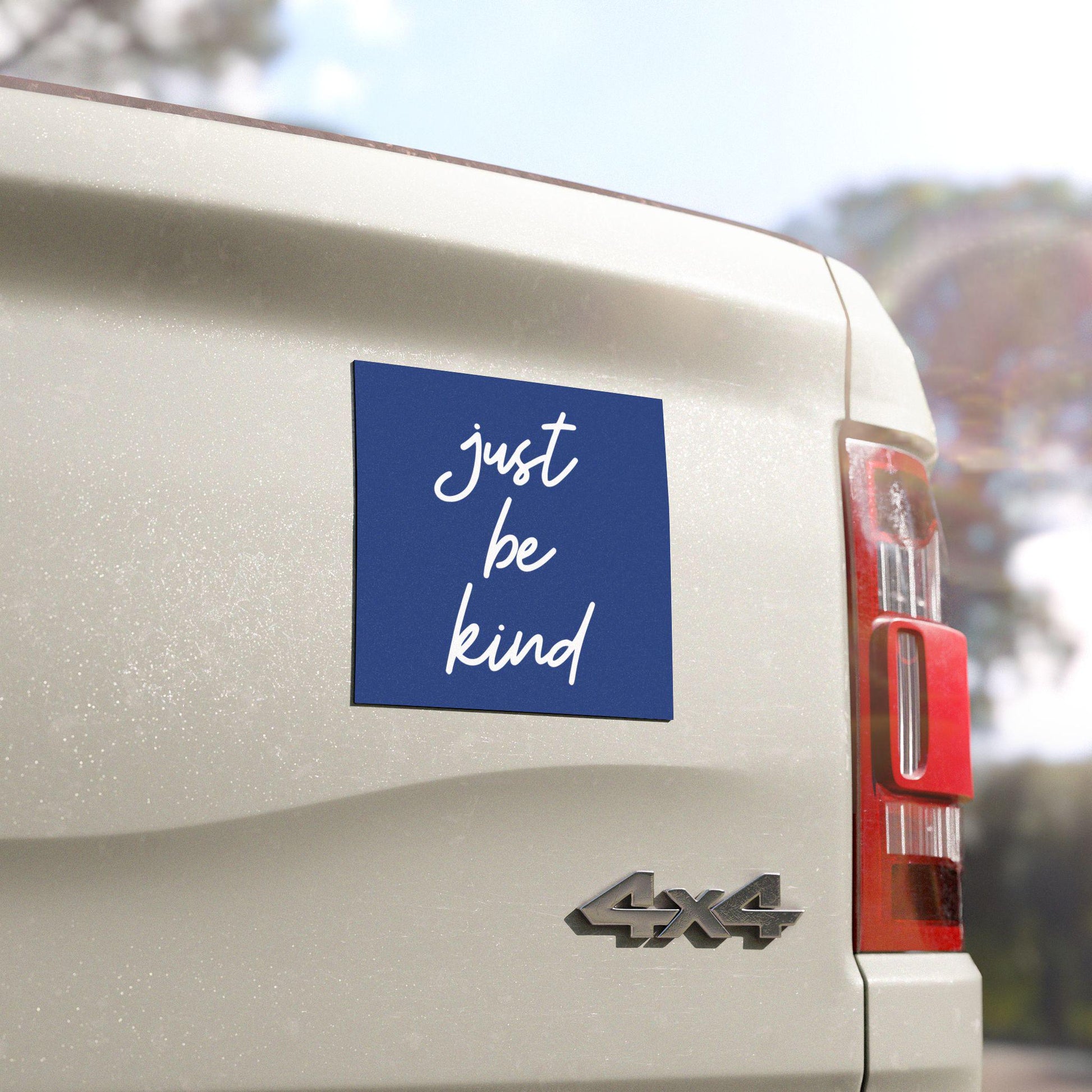 Square blue bumper magnet with white handwritten lettering that reads “Just Be Kind.”