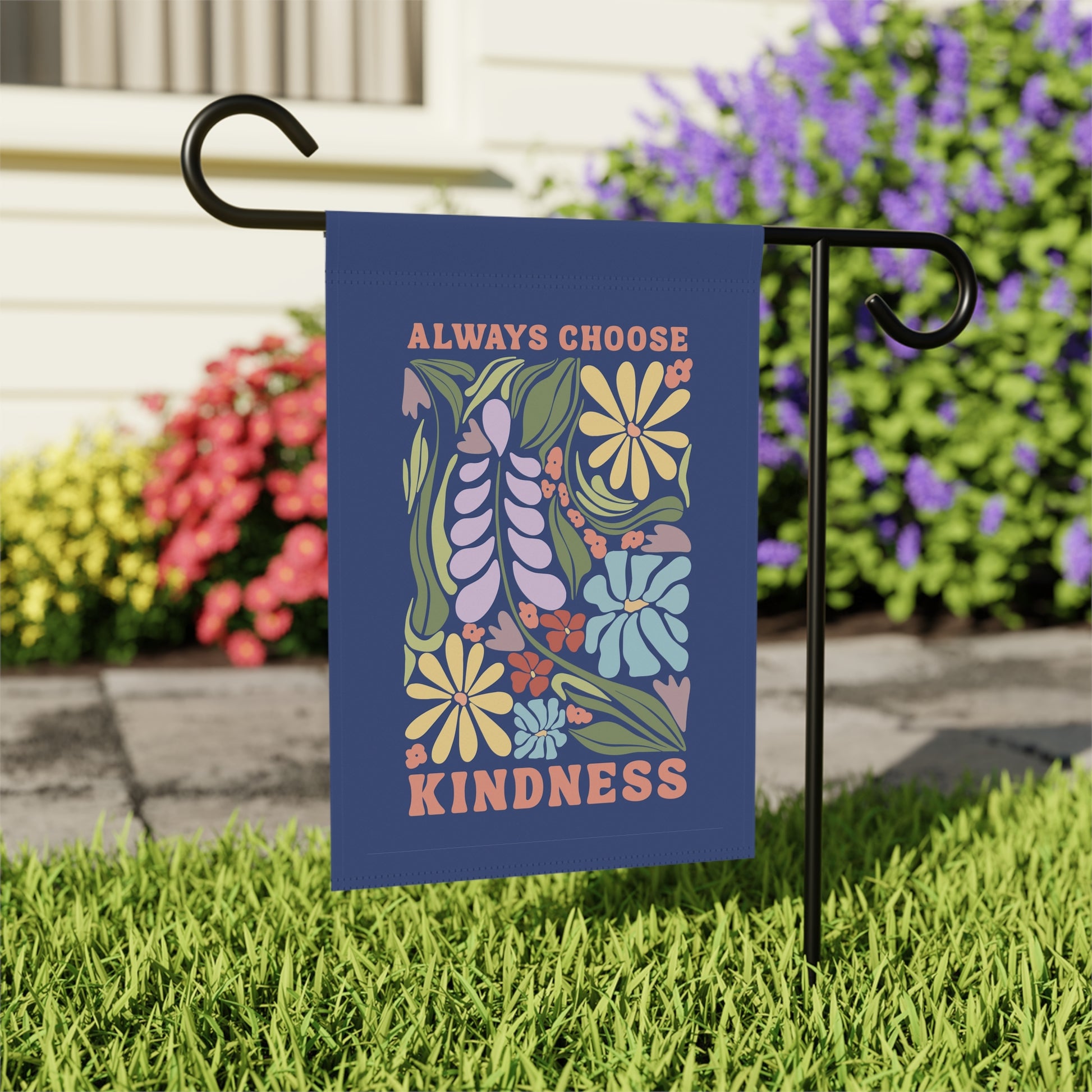 Garden flag with floral design and 'Always Choose Kindness' text on a grassy lawn.