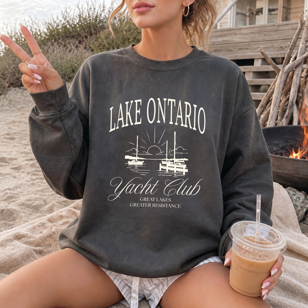 Model wearing a charcoal Lake Ontario Yacht Club crewneck sweatshirt with cream sailboat artwork and “Great Lakes Greater Resistance” lettering.