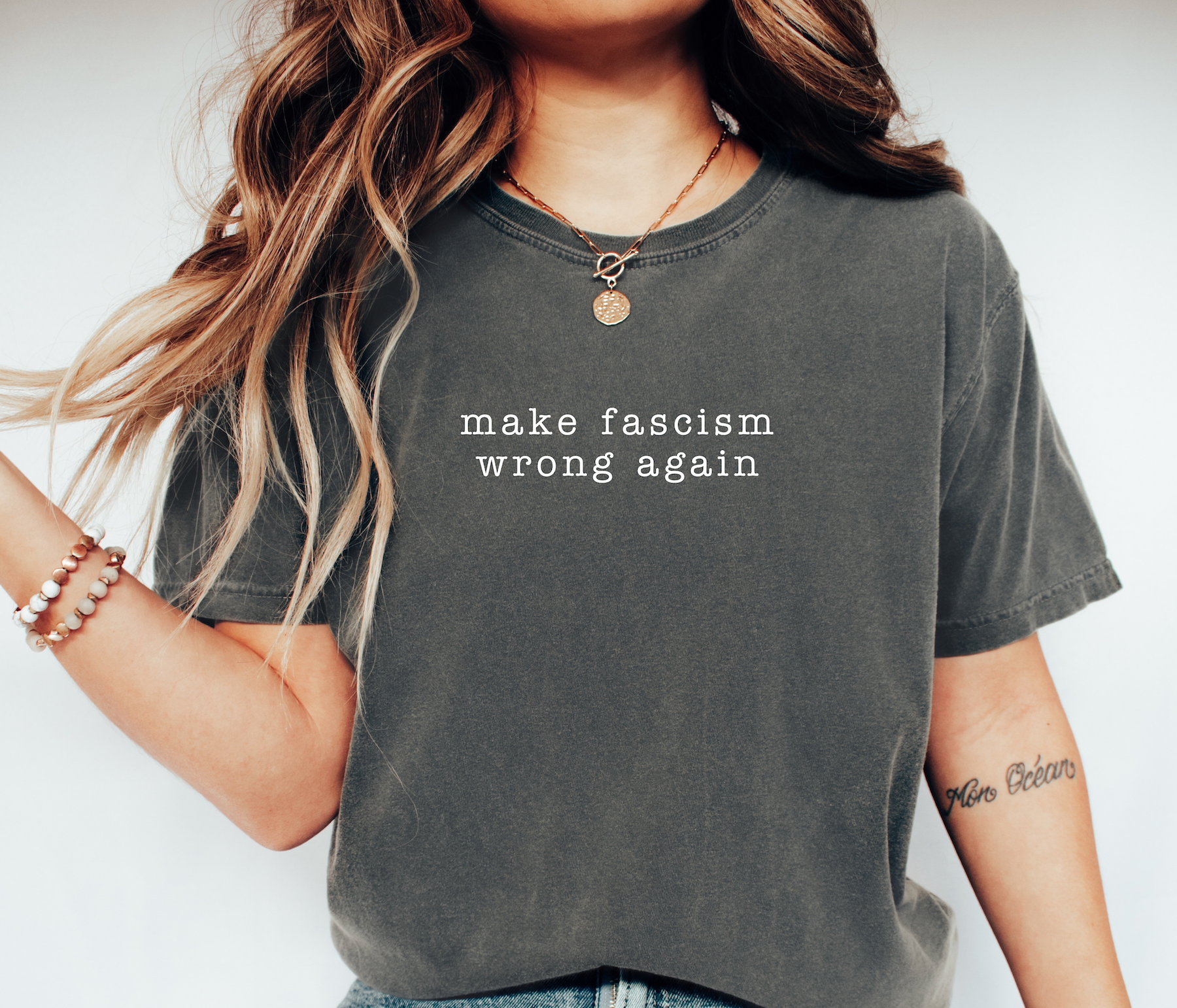 Person wearing a gray t-shirt with 'make fascism wrong again' text on a plain background