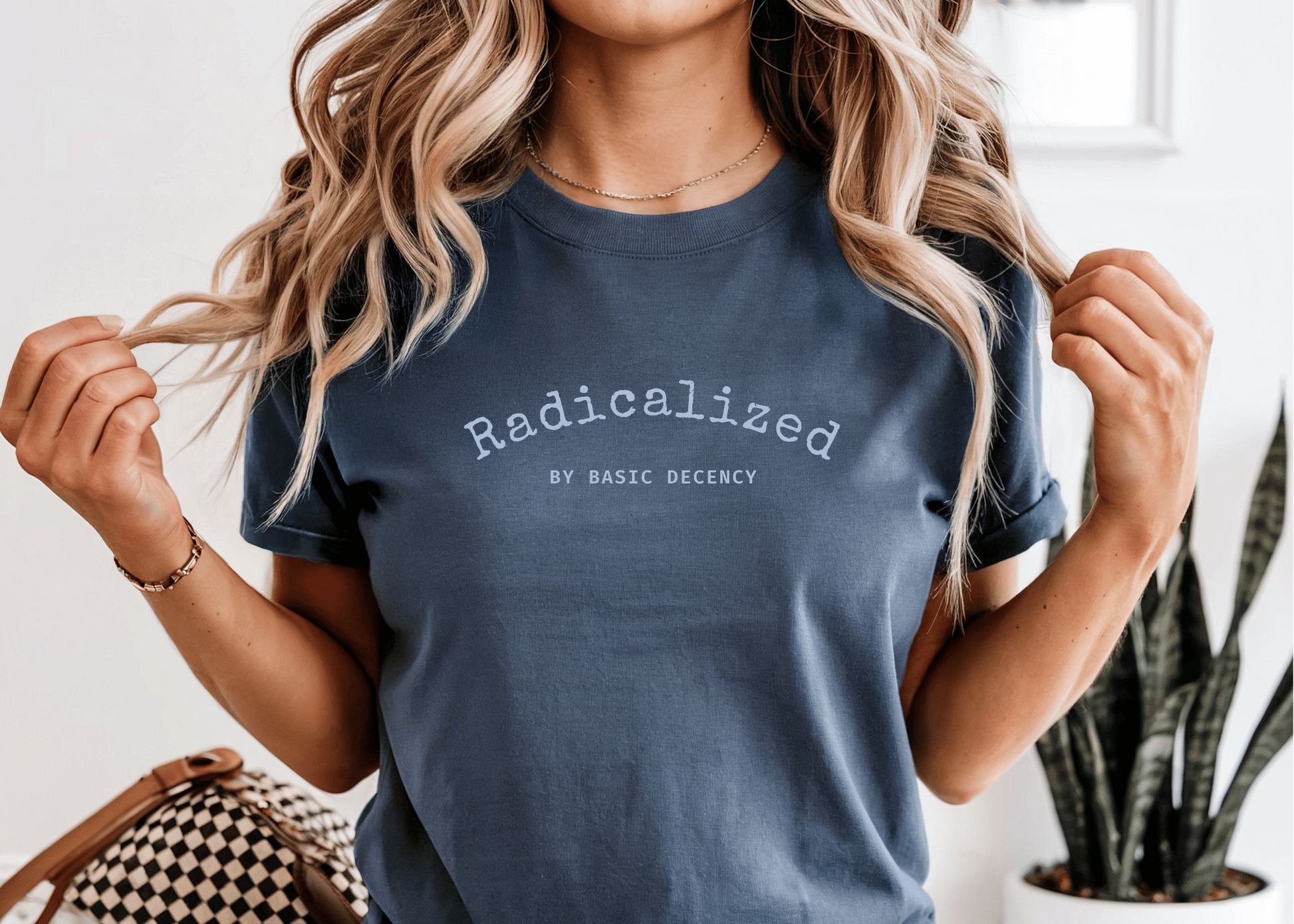 Woman wearing a navy blue t-shirt with text, sitting indoors.